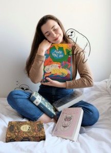 zdjęcie dziewczyny przytulającej książki, na jej ramieniu siedzi wtulony narysowany uroczy leniwiec